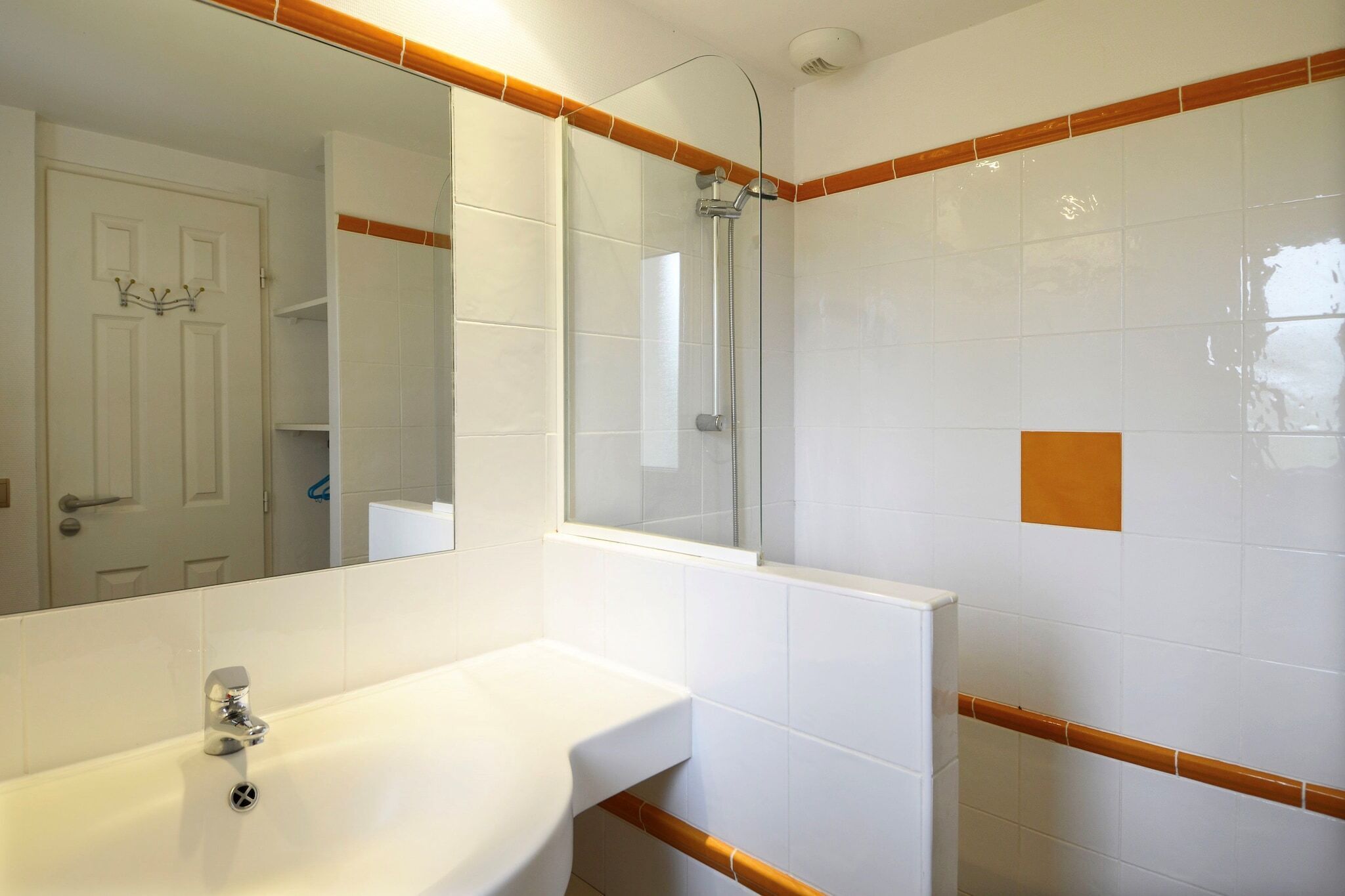 A bathroom with a white sink, a mirror, and a shower.