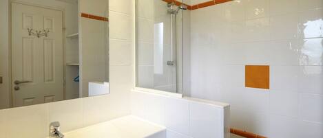 A bathroom with a white sink, a mirror, and a shower.