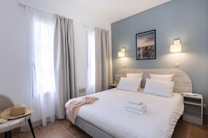 Ein Hotelzimmer mit einem Bett, einem Sessel, einem Nachttisch und einer Wandlampe.