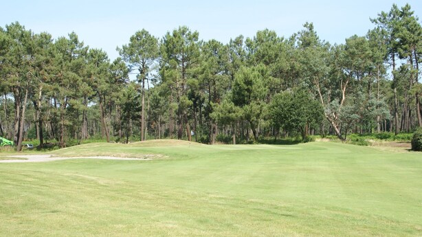 A golf course with a clear sky, surrounded by dense pine trees. - Villa in France with Golf Course & Pool (Gujan Mestras)