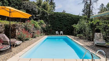 Relax by the pool surrounded by lush greenery and a natural landscape.
