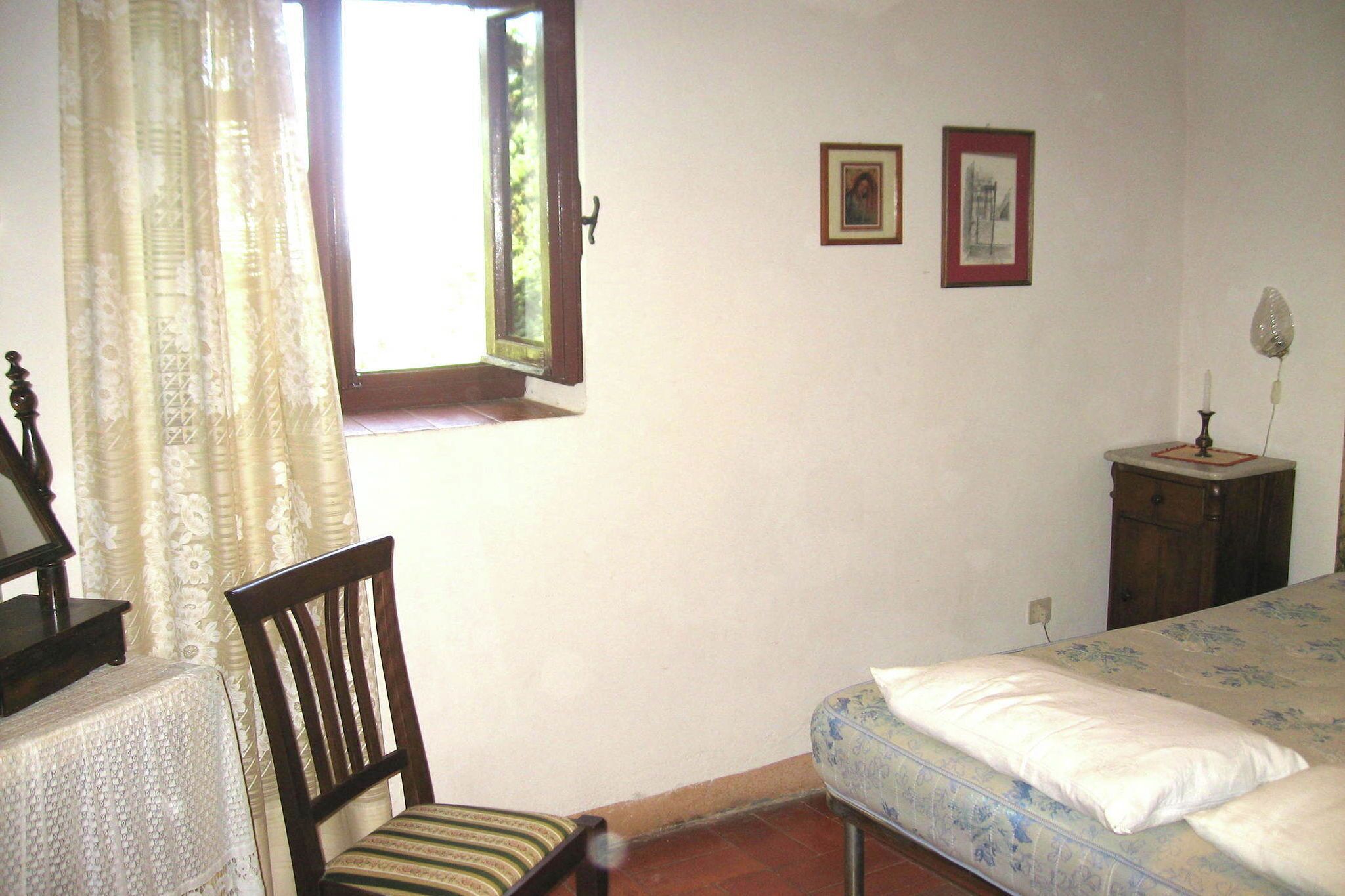 Une chambre à coucher avec un lit, une chaise, une petite table et une fenêtre avec des rideaux.