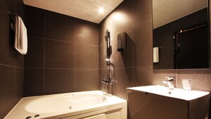 A modern bathroom with a freestanding bathtub, a vanity with a mirror, and a towel rack. - Hotel Soopil (Osan)