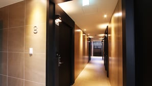 A modern hotel corridor with a wooden floor, a door with a number sign, and recessed lighting. - Hotel Soopil (Osan)