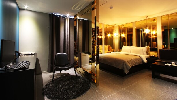 A modern hotel room with a bed, desk, chair, and a large mirror. - Hotel Soopil (Osan)