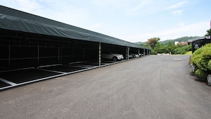 A covered parking area with multiple empty parking spaces and a clear sky. - Hotel Soopil (Osan)