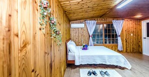 Une chambre dans une cabane en bois, avec un lit, des rideaux et une fenêtre.