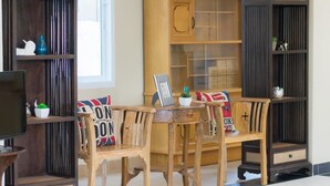 Un salon avec une table basse en bois, quatre chaises et deux bibliothèques en bois foncé ornées d’objets décoratifs.