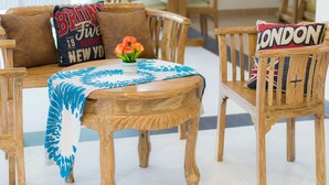 Une table à manger en bois, recouverte d’une nappe à motifs bleus et blancs, entourée de chaises en bois dotées de coussins.