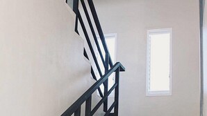 Un escalier avec des rampes noires et des carreaux de couleur beige.