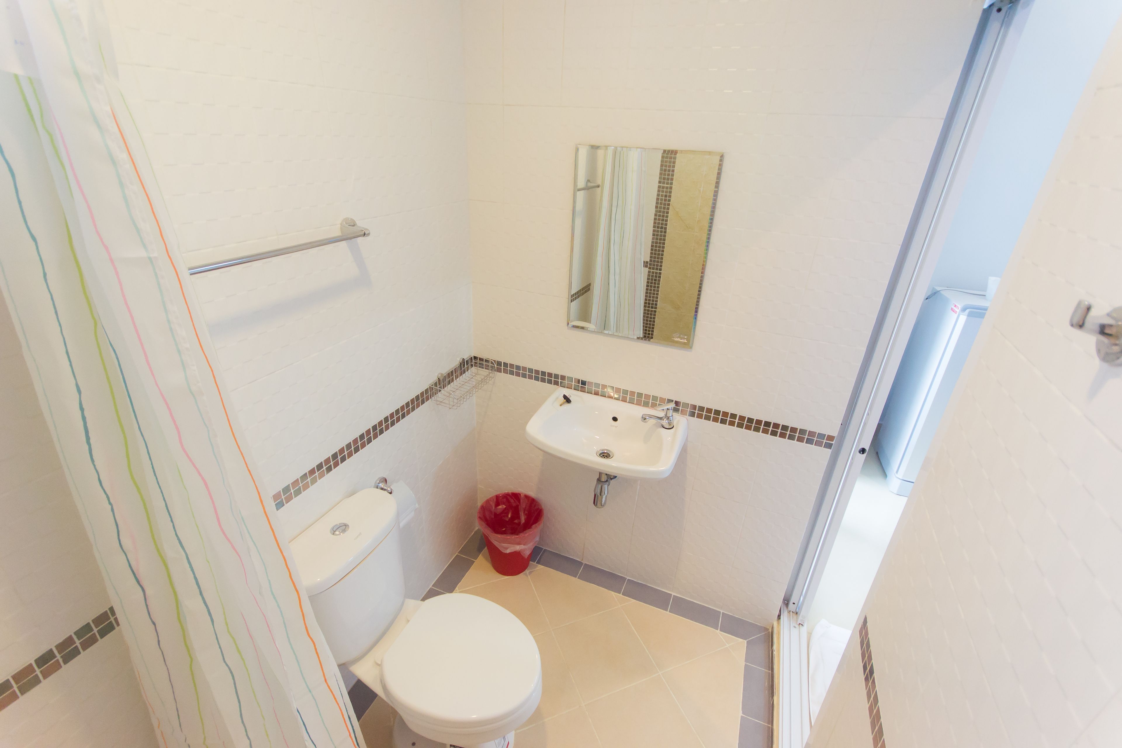 A small bathroom with a toilet, sink, and shower.