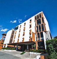 A modern hotel with a white facade, multiple balconies, and a clear blue sky.