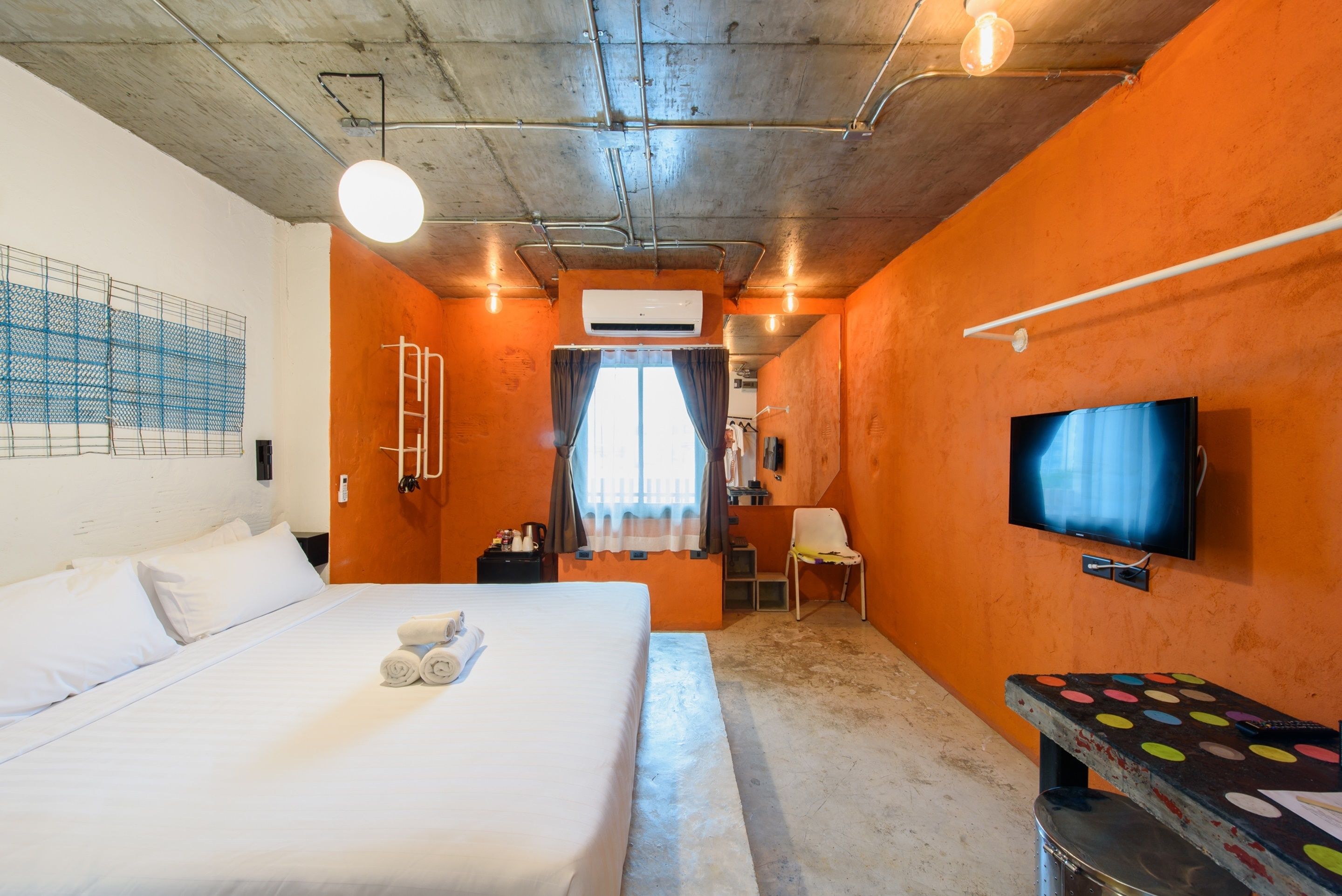 Una habitación de hotel con cama, televisión, escritorio y ventana con cortinas.