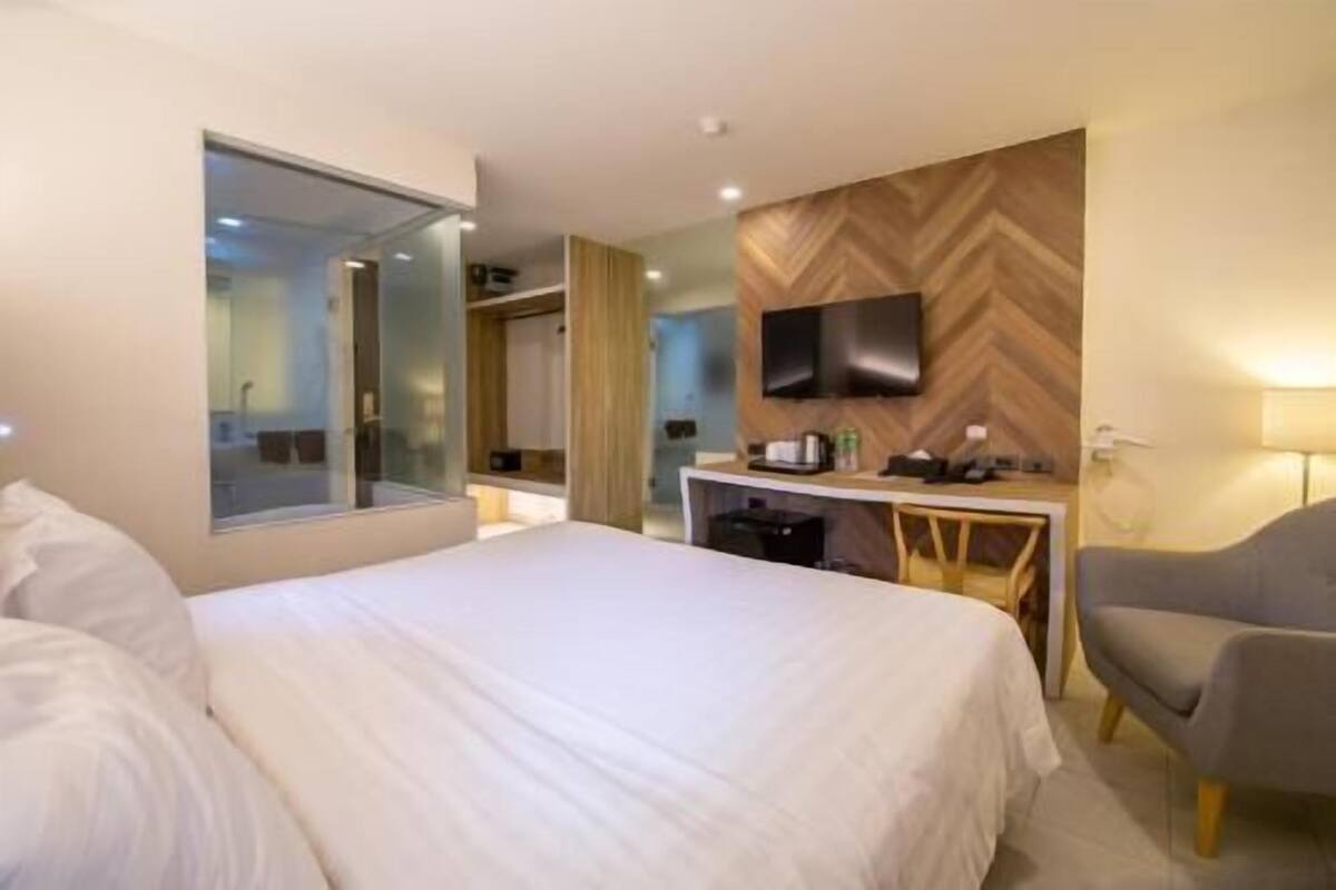 A hotel room with a bed, a desk, a chair, a TV, and a mirror.