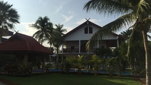 A two-story building with a red-tiled roof, surrounded by palm trees and a well-maintained lawn. - Lyndale Lodge (Sam Roi Yot)