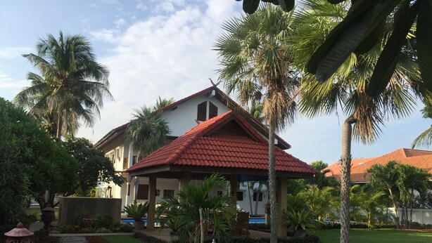 A house with a red-tiled roof, surrounded by palm trees and a stone pathway. - Lyndale Lodge (Sam Roi Yot)