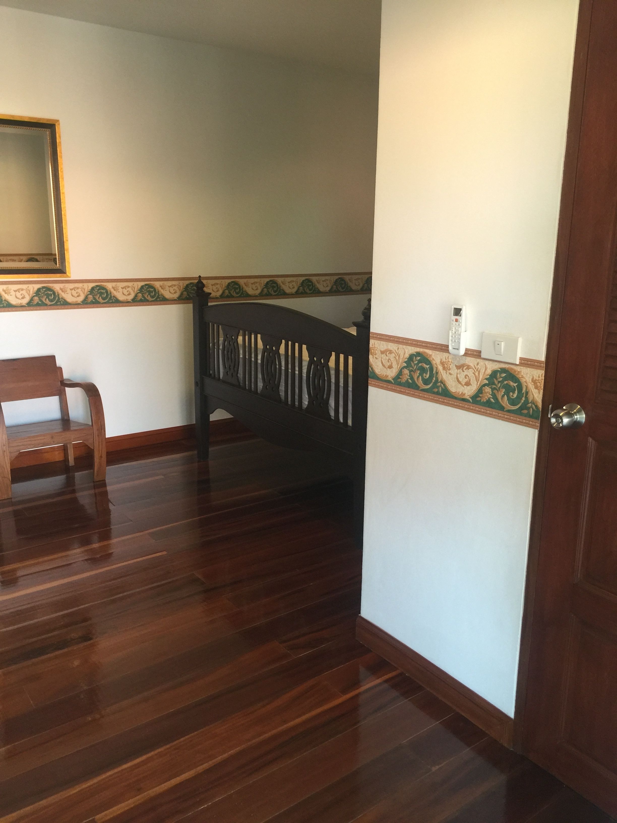 Una habitació amb terres de fusta, una panxa de fusta, una escala de fusta fosca i una porta.