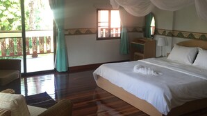 A bedroom with a large bed, a wooden nightstand, a chair, and a window with curtains. - Lyndale Lodge (Sam Roi Yot)