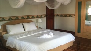 A neatly made bed with white linens, a wooden headboard, and a canopy with white fabric. - Lyndale Lodge (Sam Roi Yot)