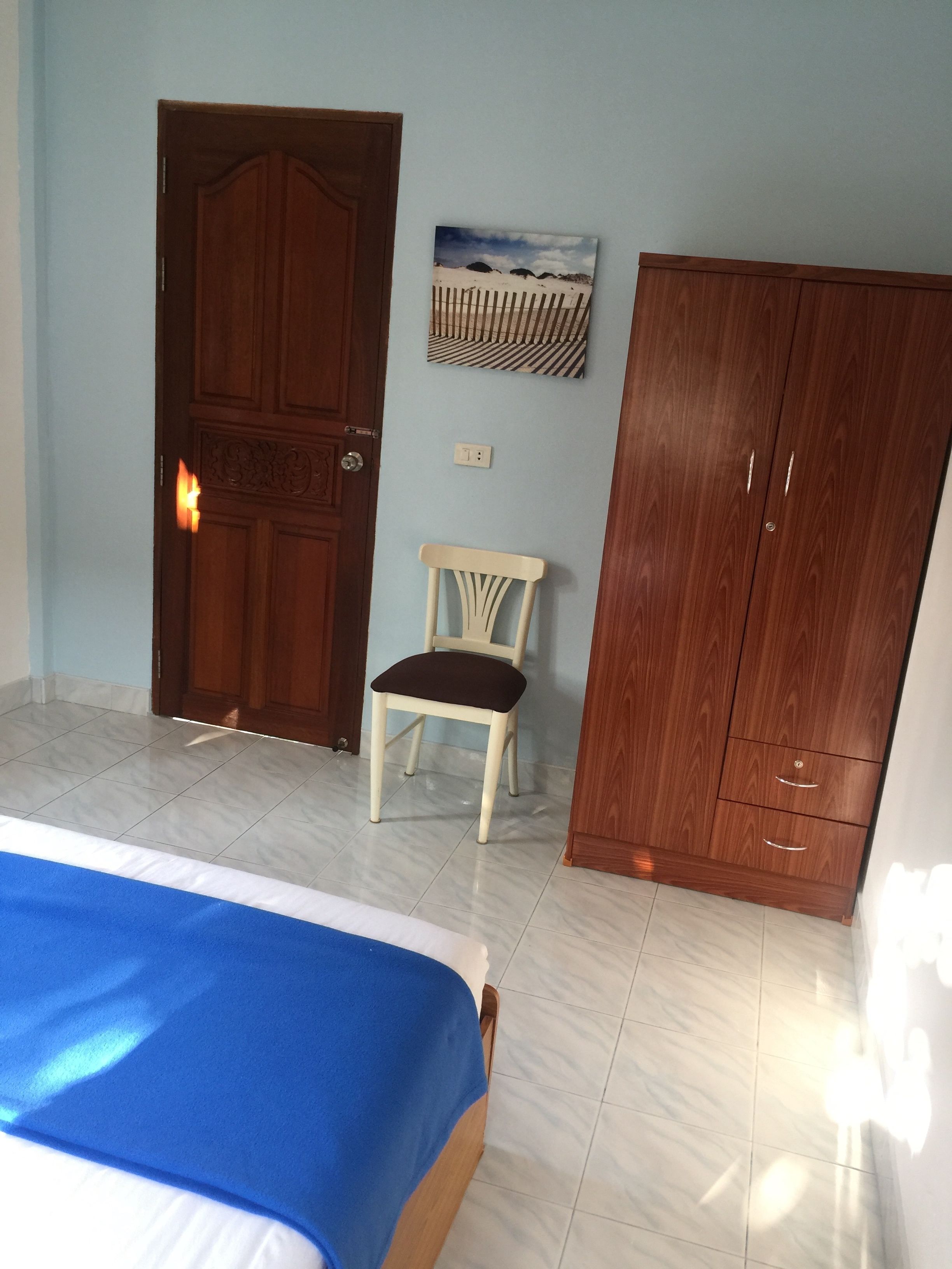 Un dormitorio con una cama, un armario de madera, una silla y un cuadro colgado en la pared.