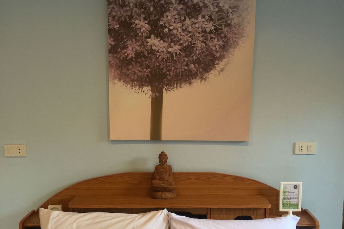 A bed with white and blue pillows, a wooden headboard, and a Buddha statue.