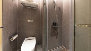 Un baño moderno con ducha de mampara de vidrio, inodoro y toallero.
