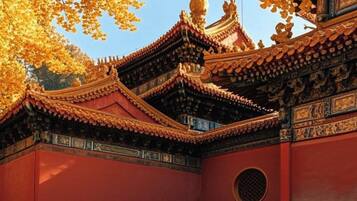 A traditional building with ornate architecture, a tiled roof, and a courtyard surrounded by fallen leaves.