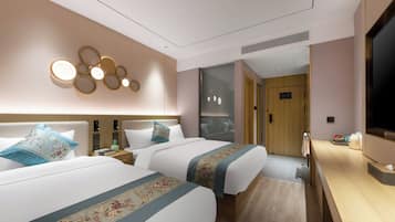 A hotel room with two beds, a TV, a desk, and a bathroom visible through a glass door.