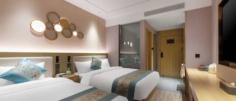 A hotel room with two beds, a TV, a desk, and a bathroom visible through a glass door.
