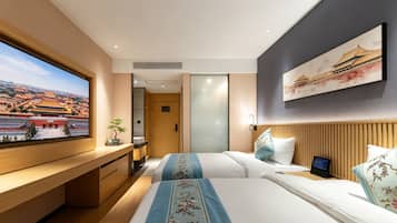 Une chambre d’hôtel avec un grand lit, un bureau donnant sur un bâtiment traditionnel et un tableau représentant un bâtiment traditionnel accroché au mur.