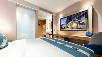 Habitación de hotel con cama, escritorio, televisión y vista al exterior del hotel.