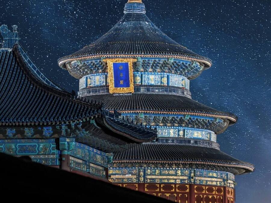 Un edificio tradicional de varios niveles con un llamativo banner azul y una luna en el cielo.