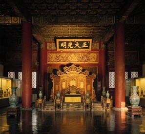 Un salón ornamentado con un altar central, pilares rojos y decoraciones chinas tradicionales.