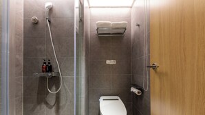 Un baño moderno con ducha acristalada, inodoro y toallero.
