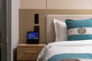 A neatly made bed with a teal pillow, a bedside table with a digital clock, and a wall panel. - East Sacred Hotel-near Beijing Tiananmen Square,the Forbidden City,Wangfujing Street-Newly renovated hotel (Beijing)