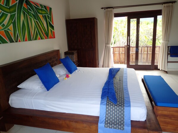A neatly made bed with blue and white bedding, a wooden headboard, and a blue patterned runner.