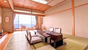 Una tradizionale stanza in stile giapponese con pavimento in tatami, un tavolino con sedie e un'ampia finestra che offre una vista.