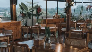 A restaurant with wooden furniture and large windows offering a view of the city. - MaxOne Hotels at Ubud (Ubud)
