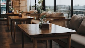 A cozy indoor seating area with wooden tables and sofas, a potted plant, and a box labeled "Mad Monkey." - MaxOne Hotels at Ubud (Ubud)