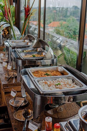 A buffet setup with multiple food stations, including rice and noodle dishes, arranged on stainless steel trays. - MaxOne Hotels at Ubud (Ubud)