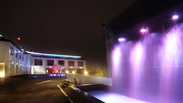 A nighttime scene with a water feature and illuminated buildings. - CoCo Motel (Puli)