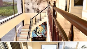 A modern staircase with wooden railings, a mural on the wall, and a view of the outdoors. - CoCo Motel (Puli)