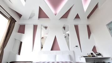 Une chambre à coucher moderne avec un plafond au design géométrique, un lit avec une literie à rayures et une table de chevet avec une lampe.