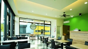 A modern dining area with tables and chairs, a food sign, and a green accent wall. - CoCo Motel (Puli)