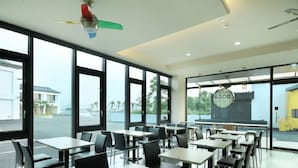 A modern dining area with large windows, a ceiling fan, and a sign indicating food services. - CoCo Motel (Puli)