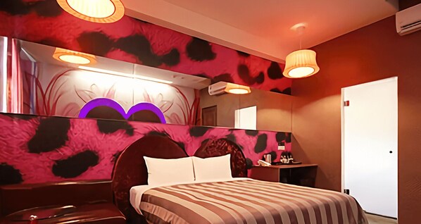 A hotel room with a large bed, a vanity with a mirror, and a desk with a chair. - CoCo Motel (Puli)