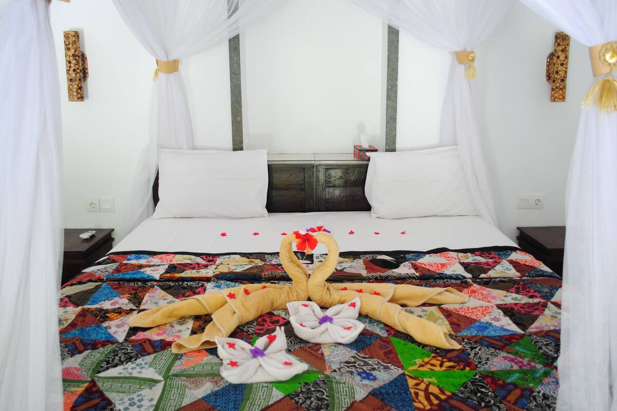 A bed with a colorful quilt, white pillows, and a canopy.