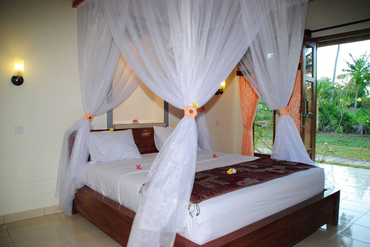 A four-poster bed with a canopy, white bedding, and a floral bedspread.
