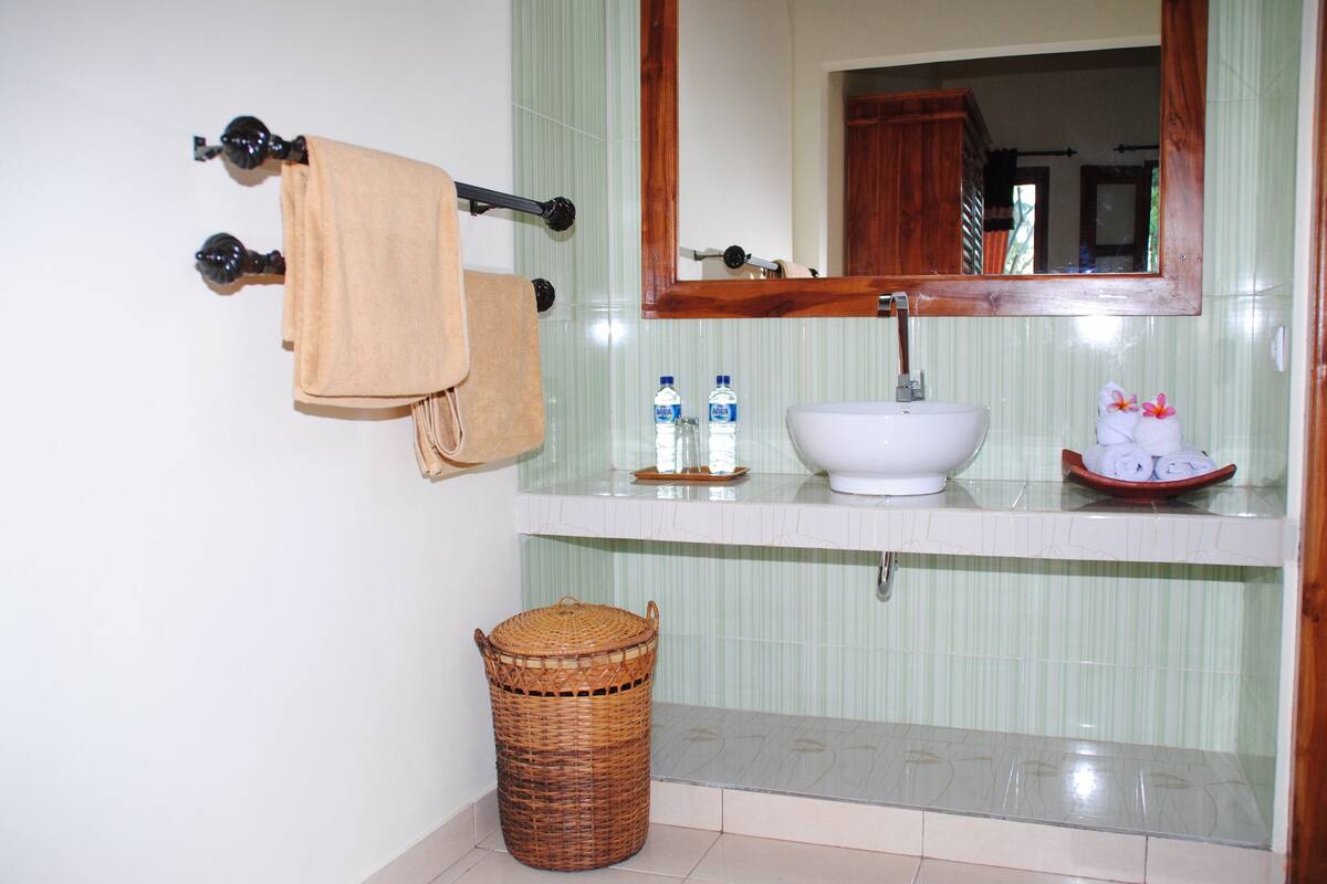A bathroom with a sink, mirror, towel rack, and a wicker basket.