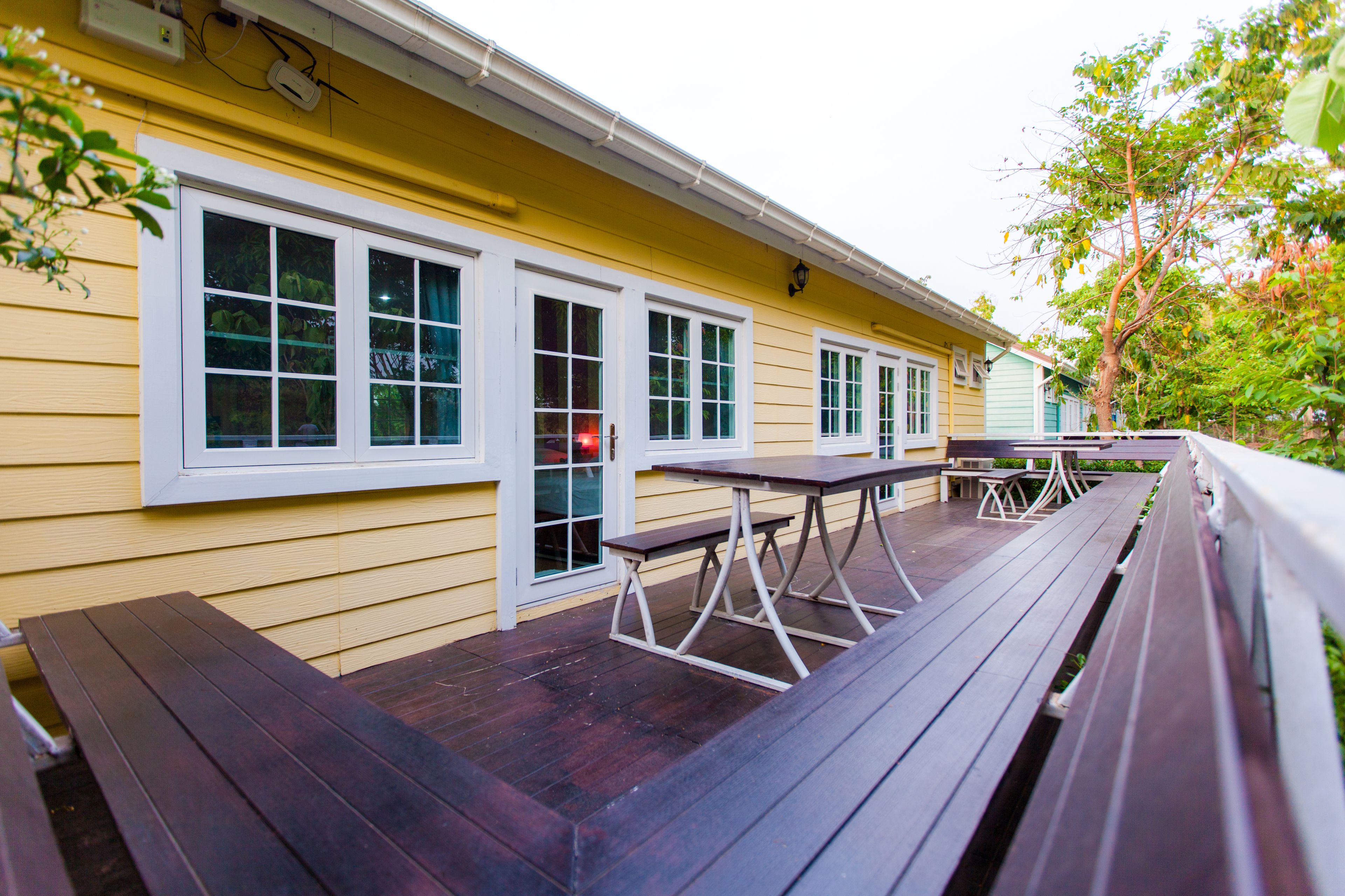 A yellow building with a wooden deck and outdoor seating.